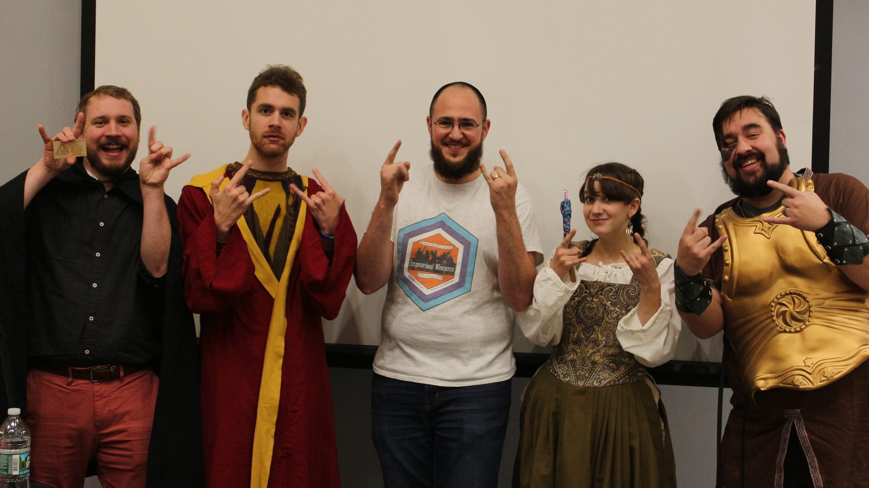 The cast of Improvised Weapons (left to right): Fred Naumann (Cassian von Daemos), Aaron Paulsen (Aaeowyn Orimora), Sam Kurnit (Your Friendly Neighborhood DM), Lindsay Haddad (Ylldove "Valyra" Cartrana), Jon van Luling (Yarfik Stormhammer) standing together, making funny faces.